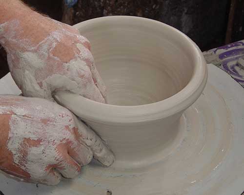 two hands working clay